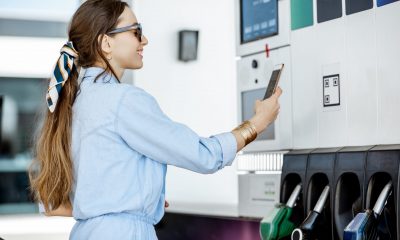 Woman paying with phone for gasoline, photographing bar code on the gas station pump